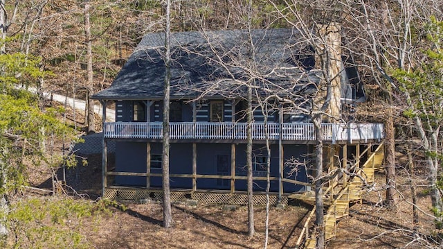 back of house featuring roof with shingles