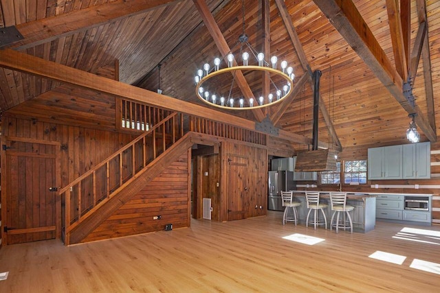 unfurnished living room featuring an inviting chandelier, light wood-style floors, and wood walls