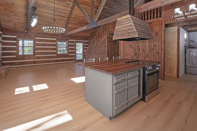 kitchen featuring washer / dryer, wooden walls, wood ceiling, butcher block countertops, and range with electric stovetop