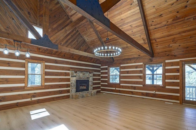 unfurnished living room with wood walls, a fireplace, beam ceiling, and a notable chandelier