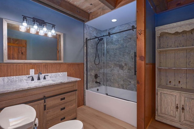 bathroom with toilet, wooden walls, vanity, shower / washtub combination, and wainscoting