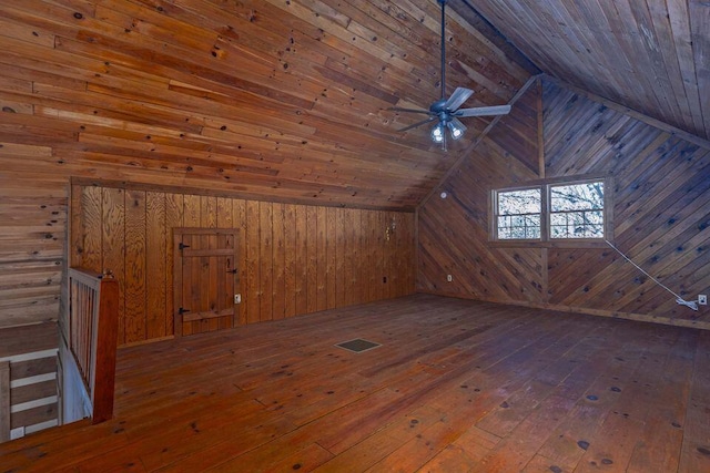 bonus room featuring lofted ceiling, wood walls, wood-type flooring, and visible vents