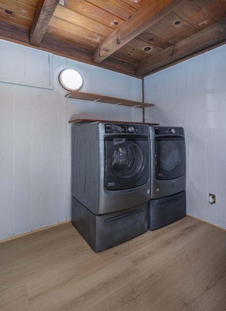 laundry area with laundry area, wood ceiling, washer and clothes dryer, and wood finished floors