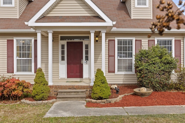 view of exterior entry featuring a shingled roof