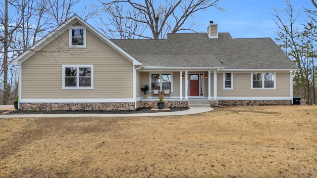 view of front of home featuring a front yard, a chimney, a porch, and roof with shingles