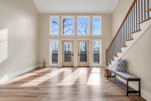 foyer entrance featuring crown molding, stairway, baseboards, and wood finished floors