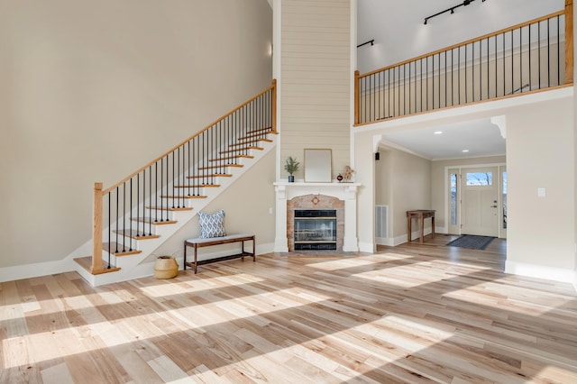 unfurnished living room with stairway, wood finished floors, a towering ceiling, and baseboards