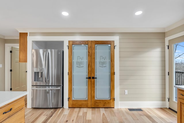 kitchen with light wood-type flooring, light countertops, french doors, and stainless steel fridge