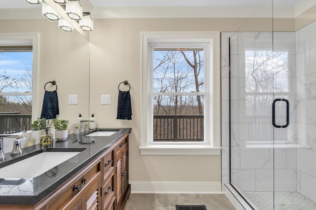 full bathroom featuring a stall shower, a sink, baseboards, and double vanity