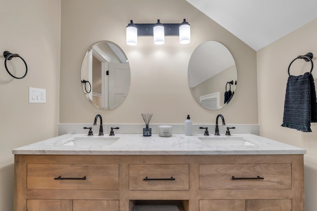 bathroom featuring vaulted ceiling, a sink, and double vanity