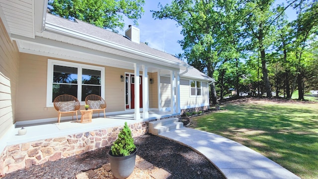 doorway to property featuring a shingled roof, a chimney, a yard, and a porch