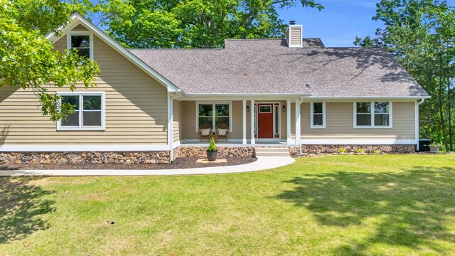 view of front of house featuring a porch, a shingled roof, a front lawn, and a chimney