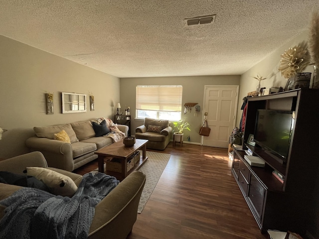 living room featuring baseboards, a textured ceiling, visible vents, and dark wood-style flooring