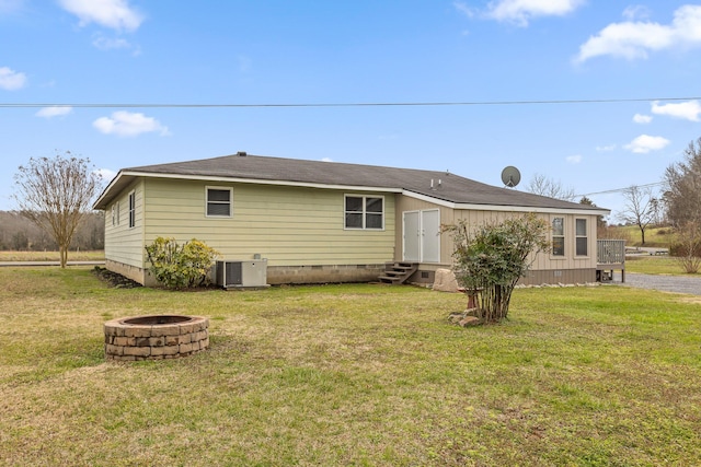 rear view of house featuring entry steps, central AC unit, a fire pit, a lawn, and crawl space