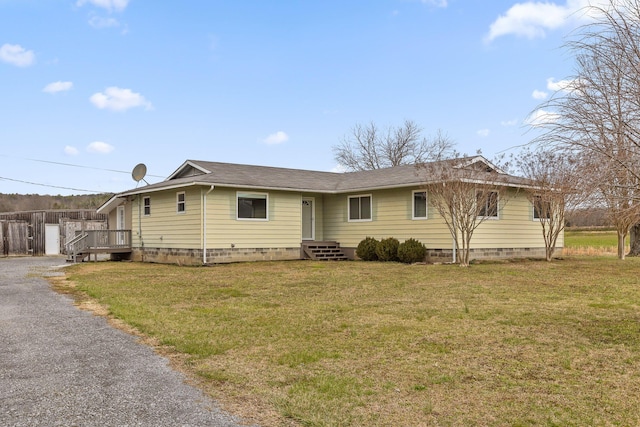 view of front facade with driveway, fence, a front lawn, and roof with shingles