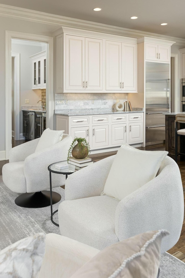 living area featuring indoor wet bar, crown molding, wood finished floors, and recessed lighting