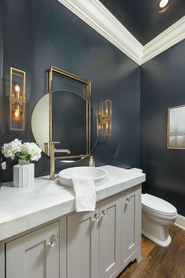 bathroom with wood finished floors, toilet, ornamental molding, and vanity