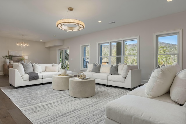 living room with visible vents, wood finished floors, recessed lighting, an inviting chandelier, and baseboards