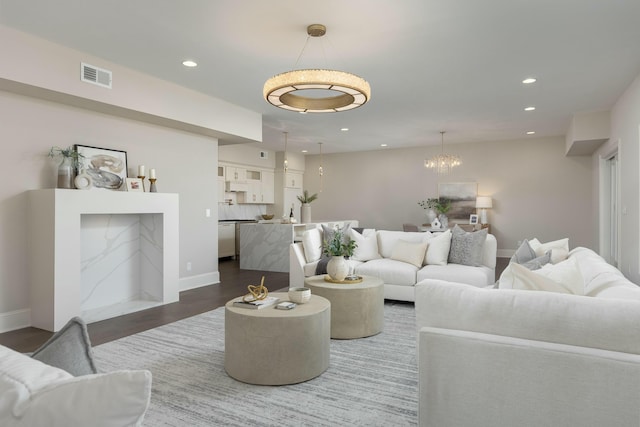 living area featuring visible vents, dark wood-type flooring, baseboards, recessed lighting, and an inviting chandelier