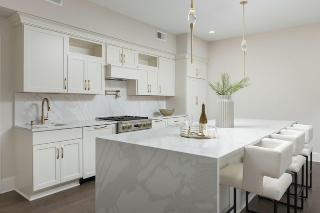 kitchen featuring visible vents, backsplash, extractor fan, white cabinets, and a sink