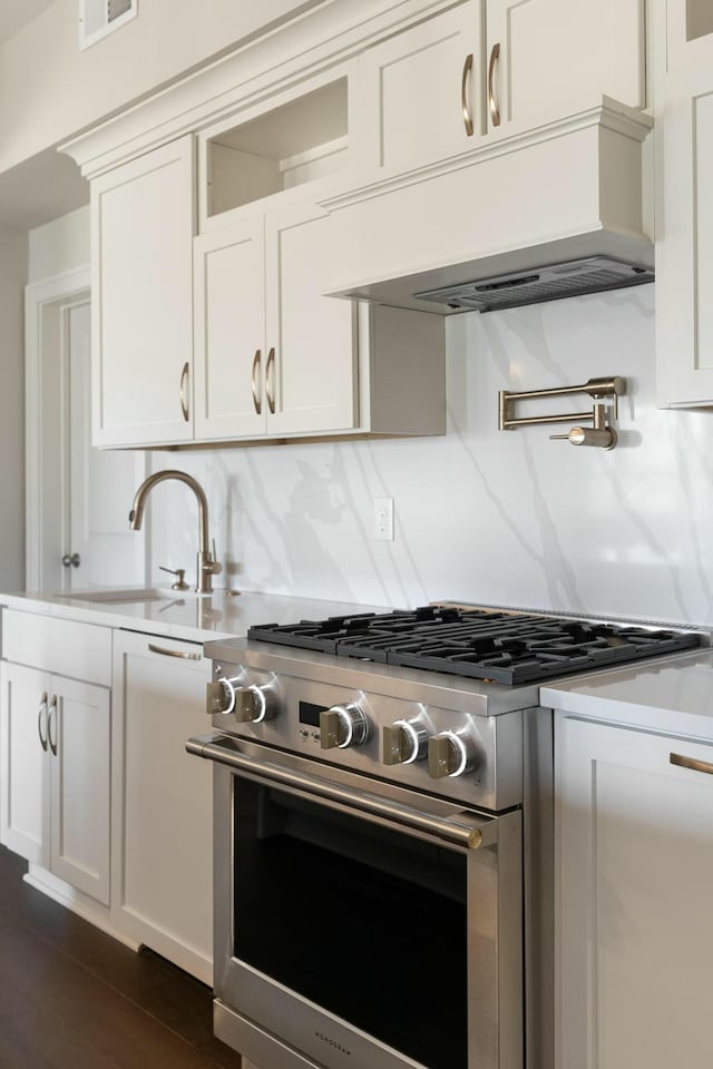 kitchen featuring a sink, tasteful backsplash, white cabinetry, stainless steel stove, and light countertops