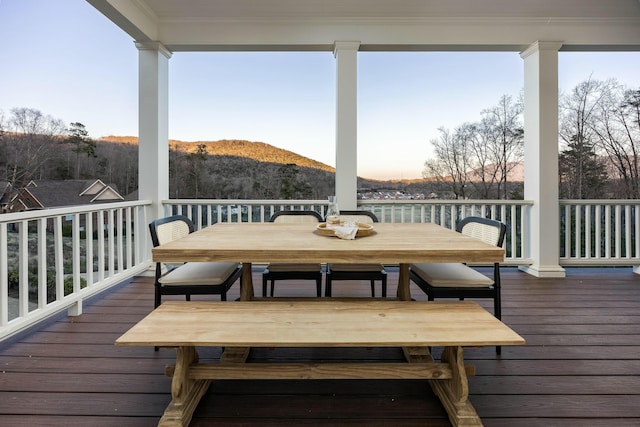 deck at dusk featuring outdoor dining space and a mountain view