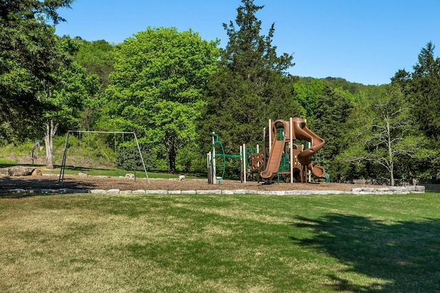 communal playground featuring a yard and a view of trees