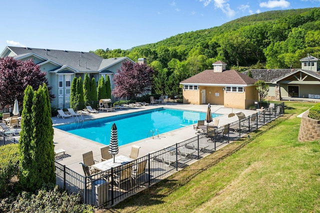 pool with a wooded view, a patio, and fence