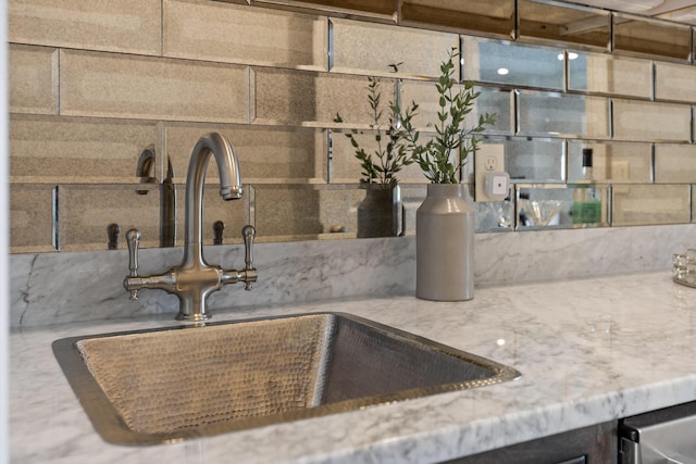 interior details with light stone counters, backsplash, and a sink