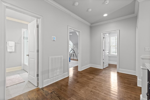 foyer entrance featuring visible vents, baseboards, wood finished floors, and crown molding