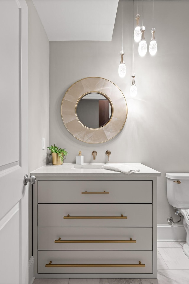 bathroom featuring vanity, toilet, baseboards, and marble finish floor