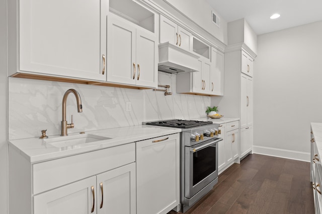 kitchen featuring visible vents, custom exhaust hood, a sink, high end stove, and tasteful backsplash