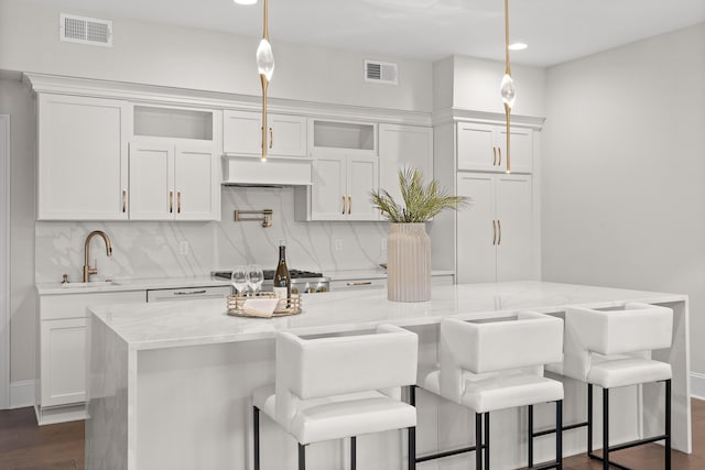 kitchen featuring a sink, visible vents, backsplash, and white cabinetry