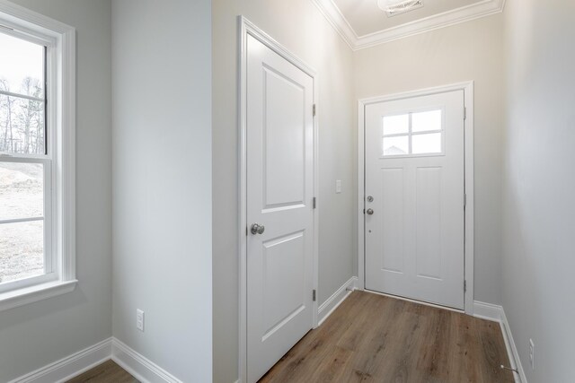 doorway to outside with ornamental molding, baseboards, and wood finished floors