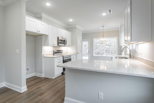 kitchen featuring a peninsula, appliances with stainless steel finishes, white cabinets, and a sink
