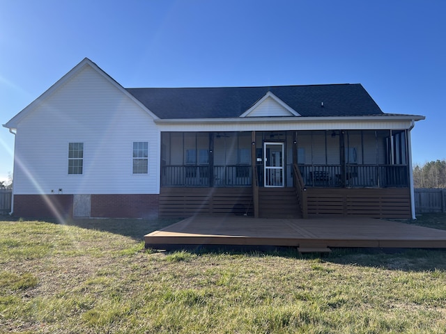 rear view of house with a yard, a wooden deck, and a sunroom