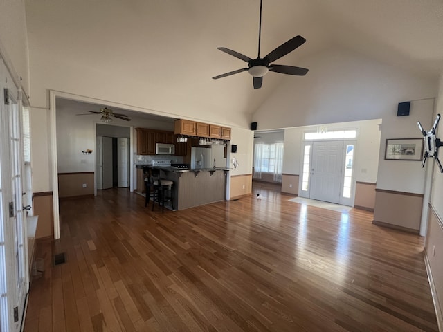 unfurnished living room with dark wood-style floors, high vaulted ceiling, ceiling fan, and visible vents