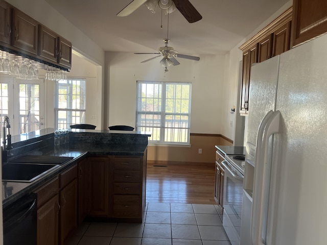 kitchen featuring dark countertops, white appliances, plenty of natural light, and light tile patterned floors