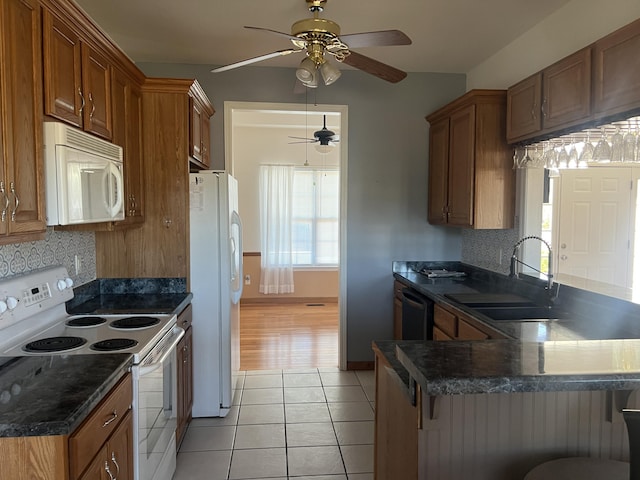 kitchen featuring white appliances, light tile patterned flooring, a sink, and brown cabinets