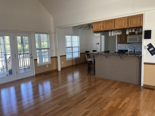 kitchen featuring brown cabinets, white microwave, a sink, wood finished floors, and a kitchen bar