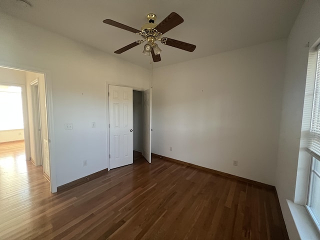 unfurnished bedroom featuring multiple windows, baseboards, and wood finished floors