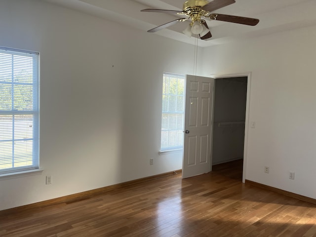 empty room with ceiling fan, wood finished floors, and baseboards