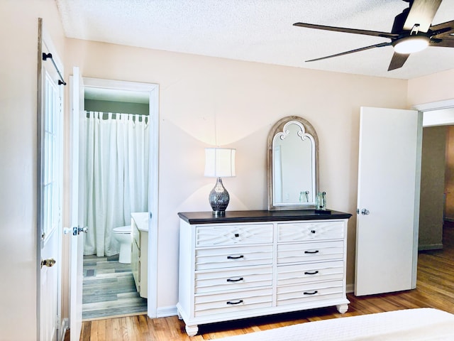 bedroom featuring light wood-style flooring, ceiling fan, a textured ceiling, and ensuite bathroom