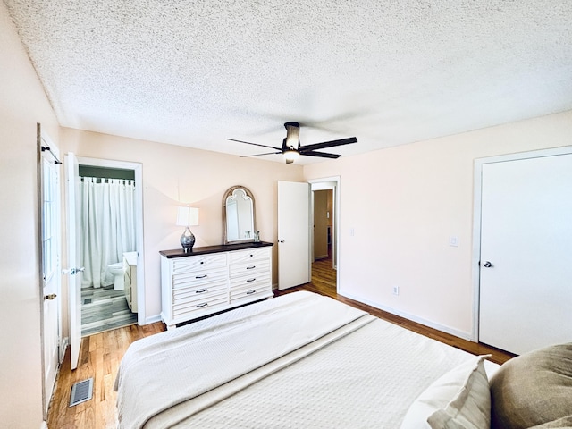 bedroom with a textured ceiling, ceiling fan, ensuite bathroom, visible vents, and light wood-style floors