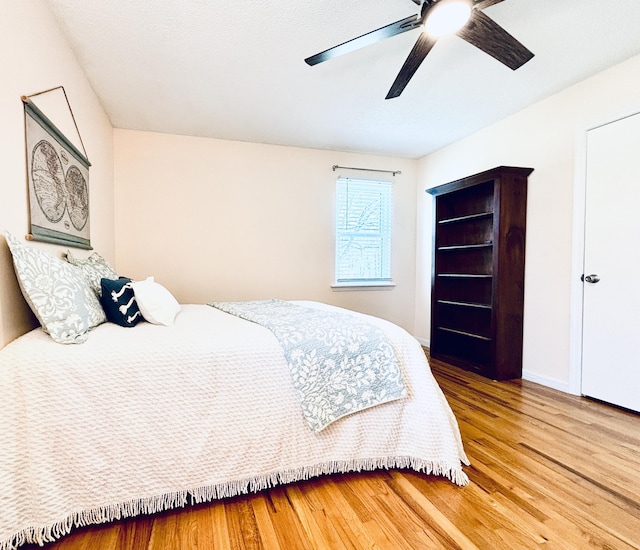 bedroom featuring wood finished floors, a ceiling fan, and baseboards