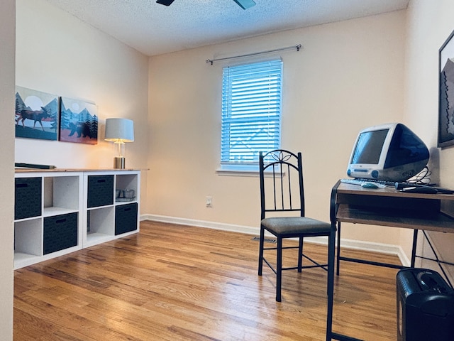 office space featuring ceiling fan, a textured ceiling, baseboards, and wood finished floors