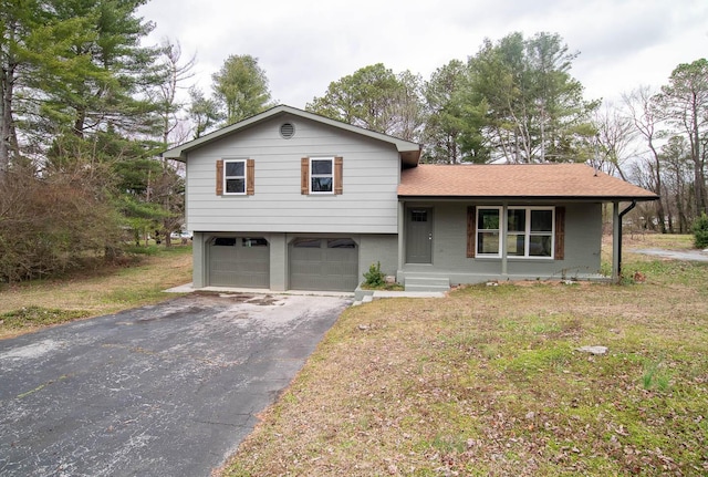 split level home featuring aphalt driveway, brick siding, roof with shingles, a garage, and a front lawn