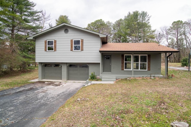 split level home with aphalt driveway, brick siding, an attached garage, and a front lawn