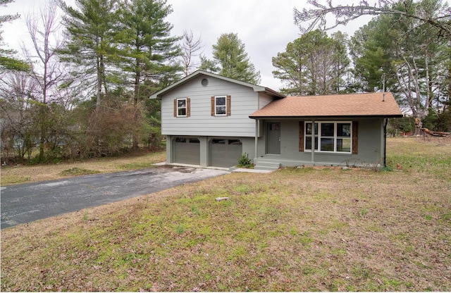 split level home featuring a porch, a garage, driveway, roof with shingles, and a front yard