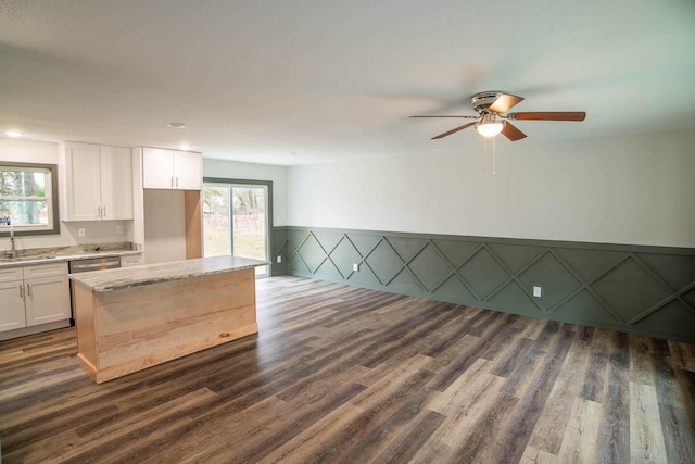 kitchen featuring dark wood-style flooring, a sink, white cabinetry, light stone countertops, and dishwasher